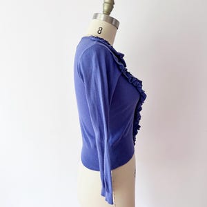 Op de afbeelding: Een periwinkelblauwe cardigan met lange mouwen en een gefranjerde rand aan de voorkant. De lichtgewicht knitwear wordt gepresenteerd op een mannequin tegen een witte achtergrond. De cardigan is een klassieke stijl.