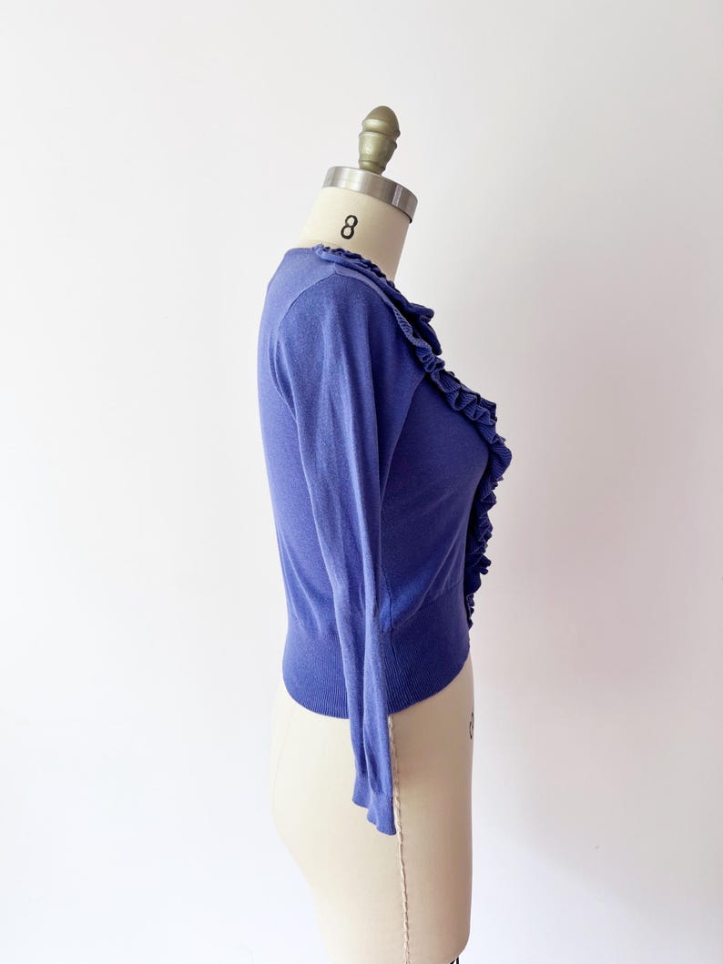 Op de afbeelding: Een periwinkelblauwe cardigan met lange mouwen en een gefranjerde rand aan de voorkant. De lichtgewicht knitwear wordt gepresenteerd op een mannequin tegen een witte achtergrond. De cardigan is een klassieke stijl.