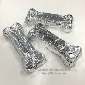 May include: Three silver foil-wrapped chocolate bones. The bones are shaped like dog bones and are a popular treat for dogs.