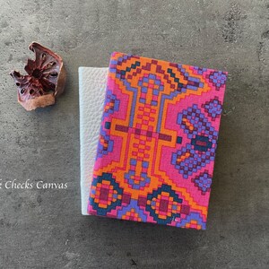May include: Two notebooks, one with a white cover and the other with a pink, orange, and purple geometric pattern. The text "Pink Checks Canvas" is visible on the bottom left of the image.
