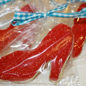 May include: Three red glitter high heel shoe cookies wrapped individually in clear plastic bags tied with blue and white gingham ribbon.