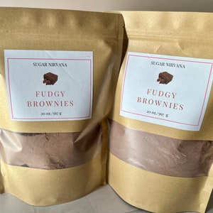 May include: Two brown paper bags with white labels that say "Sugar Nirvana" and "Fudgy Brownies" with a picture of a brownie. The bags contain a brown powder and the labels say "20 oz./567 g".