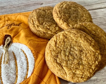 May include: Four soft, golden brown pumpkin spice cookies on a yellow and white quilted fabric with a pumpkin design.