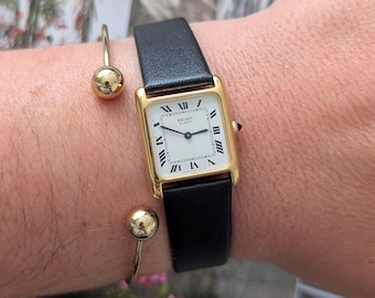 Vintage SEIKO goudkleurig tankkwartshorloge met nieuwe zwarte leren band, zwarte kroon en nieuwe batterij.  Past het beste om een pols van 7 inch of kleiner.