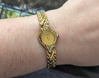 Reloj Samsung vintage de cuarzo en tono dorado con bisel redondo, detalles de cristal y batería nueva. Ideal para muñecas de hasta 18 cm (7 pulgadas).
