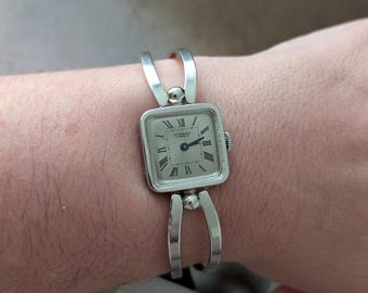 Vintage LA MARQUE Silver Tone Winding Tank Watch with Silver Face, Black Details. Best fits 6.5” wrist or smaller.