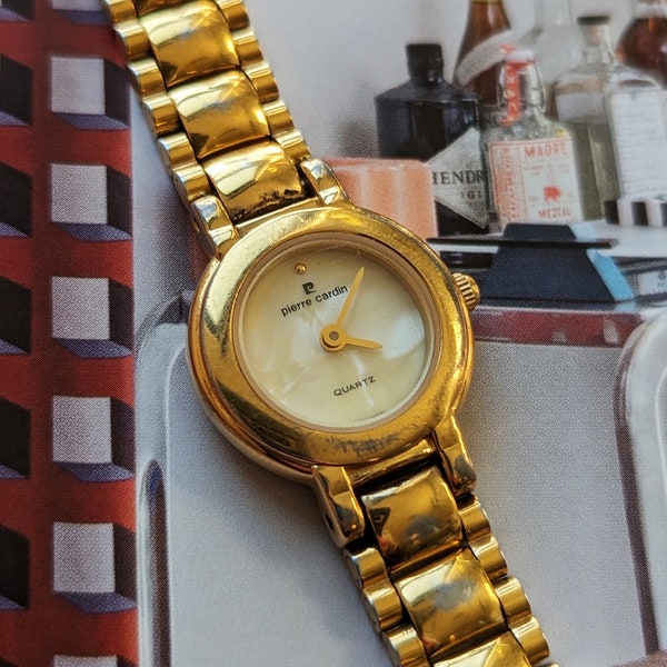 Vintage Gold Pierre Cardin Watch Featuring Pearl Face with New Battery. Best fits 6.5” wrist or smaller.