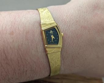 Vintage CITIZEN Gold Tone Quartz Watch with a Half Moon Shaped Black Face and New Battery. Best fits 7” wrist or smaller. This is in like ne