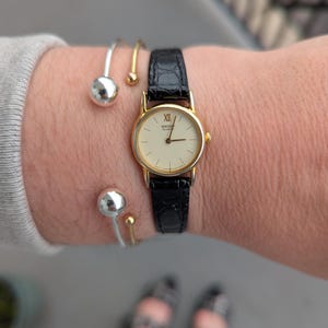 Vintage SEIKO Gold Tone Quartz Watch with White Face, New Old Stock Black Leather Band and New Battery.  Best fits 7” wrist or smaller.