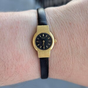 Vintage SEIKO Gold Tone Quartz Watch with Black Face, New Black Leather Band and New Battery.  Best fits 7” wrist or smaller.