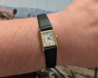 Mini montre à quartz SEIKO vintage tank ton or avec nouveau bracelet en cuir noir et batterie neuve.  Convient parfaitement à un poignet de 7,5 pouces ou moins.