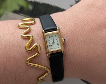 Vintage RILA Gold Tone Tank Winding Watch with New Black Leather Band.  Best fits 7.5” wrist or smaller.