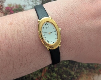 Vintage SEIKO with Large Oval Gold Tone Face, New Black Leather Band and New Battery. This Best fits 7.5” wrist or smaller.