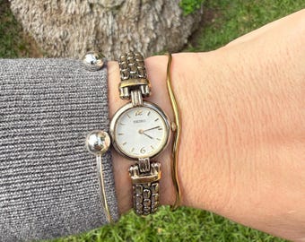 Vintage SEIKO Two Tone Quartz Watch with Round Face and New Battery. Best fits 7” wrist or smaller.