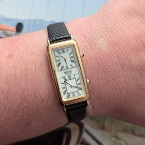 Vintage SEIKO guldfärgad kvartsklocka med dubbla urtavlor, nytt svart läderarmband och nytt batteri. Passar bäst handled upp till 7,5 tum.