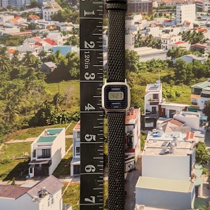 May include: A vintage Citizen Quartz watch with a black textured band and silver buckle. The watch face displays the time as 4:27. The watch is approximately 8 inches long, measured with a black ruler.