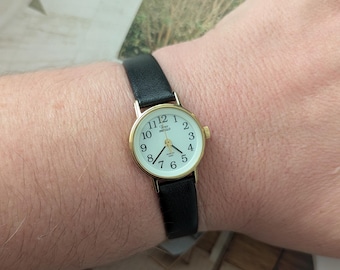 Vintage TIMEX Gold Tone Quartz Watch with New Black Leather Band and New Battery. Best fits up to 6.5” wrist or smaller.