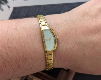 Vintage TIMEX Gold Tone Quartz Watch with a Half Moon Shaped Bezel,Crystal Detail and New Battery. Best fits 6” wrist or smaller.