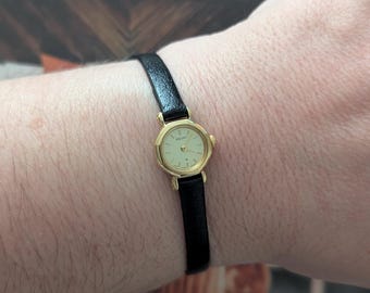 Vintage SEIKO Gold Tone Tiny Face Quartz Watch with New Black Leather Band, Original Box and New Battery. Best fits 6.5” wrist or smaller.
