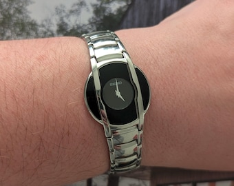 Vintage Seiko Silver Tone Quartz Watch with Round Face, Black Dial and New Battery. Best fits 7” wrist or smaller.