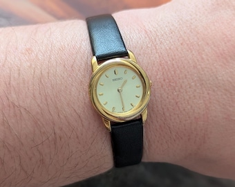 Vintage SEIKO Gold Tone Round Quartz Watch with Original Box, New Black Leather Band and New Battery.  Best fits 6.5” wrist or smaller.