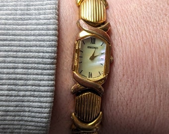 Vintage SEIKO Gold Tone Quartz Watch with  Pealescsent face and New Battery. Best fits 6.5 wrist or smaller.