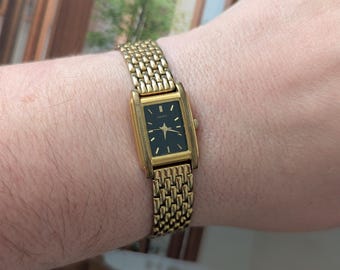 Vintage Seiko Gold Tone Quartz Watch with Black Dial and New Battery.  Best fits 6” wrist or smaller.