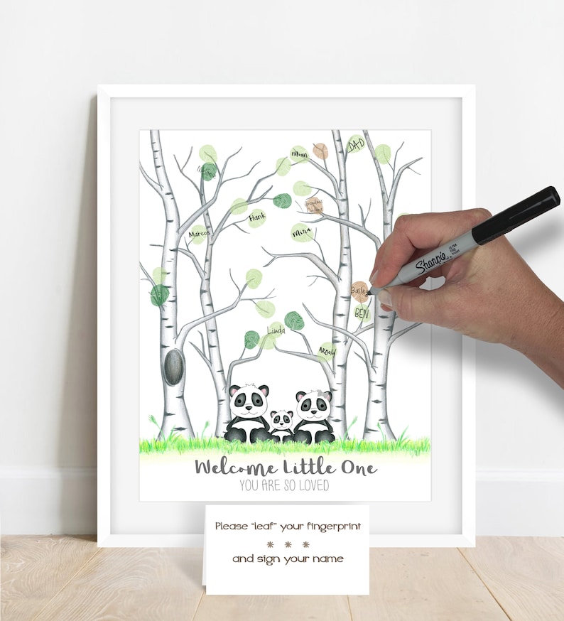 May include: A framed print featuring a family of pandas beneath birch trees with green leaves. The words "Welcome Little One, You Are So Loved" are at the bottom. A person is using a black marker to add a fingerprint and name to the tree.