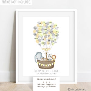 Puede incluir: Un marco blanco con una impresión de un globo aerostático hecho de globos amarillos, grises y blancos con personajes de animales. El globo lleva una jirafa, una cebra, un león y un mono. El texto "DREAM BIG, LITTLE ONE - our adventure awaits!" está impreso debajo del globo. Una tarjeta blanca con el texto "Up, up, up and away! Add your fingerprint and sign your name" está en la esquina inferior derecha de la imagen.