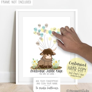 May include: A white print featuring a brown Highland cow illustration with yellow and blue fingerprint balloons attached by thin black lines. Text reads: Welcome Little One - YOU ARE SO LOVED, and ADD YOUR FINGERPRINT AND SIGN YOUR NAME to make balloons.