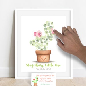 Image of a personalized fingerprint cactus showing a guest at a baby shower adding a fingerprint with green stamp pad ink to fill in the outline of a cactus, fingerprint guestbook alternative for a desert themed baby shower or birthday party