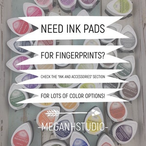 May include: A collection of Memento ink pads in various colors, including red, purple, and green, arranged on a light blue wooden surface. Text on the image reads "Need Ink Pads for Fingerprints?" and "For Lots of Color Options!"