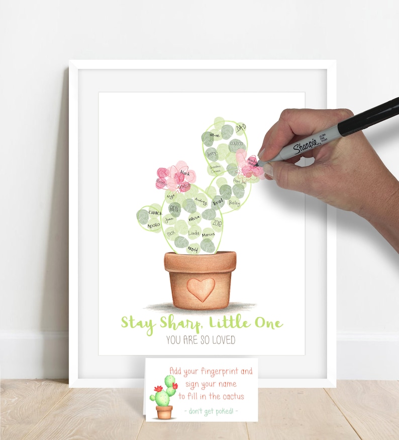 example of a guest adding their signature to their fingerprint on a fingerprint cactus guestbook alternative, fingerprints are made with stamp pad ink and used to fill in the outline of a hand drawn cactus shown in a terra cotta pot meganhstudio