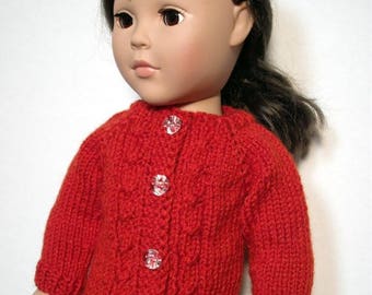 May include: A red knitted cardigan with a cable knit pattern and clear button closures. The cardigan is worn by a doll with brown hair.