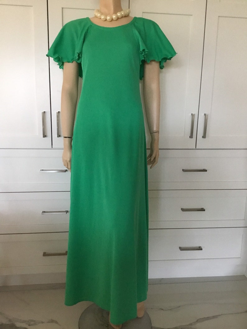 May include: A long, green maxi dress with short sleeves and a ruffled trim. The dress has a round neckline and is made of a smooth, flowing fabric.
