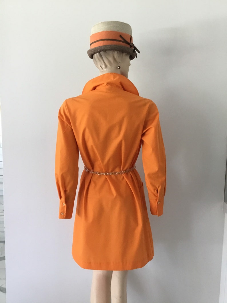 Op de afbeelding: Een feloranje getailleerde jurk met lange mouwen en een riem. De jurk heeft een eenvoudig, klassiek ontwerp en is gemaakt van een lichtgewicht stof.