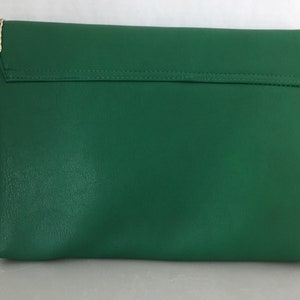 May include: A green leather clutch purse with a gold chain strap.