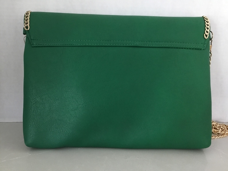 May include: A green leather clutch purse with a gold chain strap.