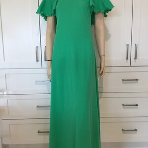 May include: A long, green maxi dress with a round neckline and short, ruffled sleeves. The dress is made of a smooth, lightweight fabric.