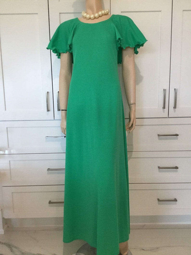 May include: A long, green maxi dress with a round neckline and short, ruffled sleeves. The dress is made of a smooth, lightweight fabric.