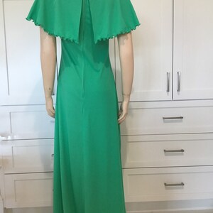 May include: A long green maxi dress with a cape-like collar and short sleeves. The dress has a zipper down the back.