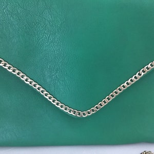May include: A green leather clutch bag with a silver chain strap.