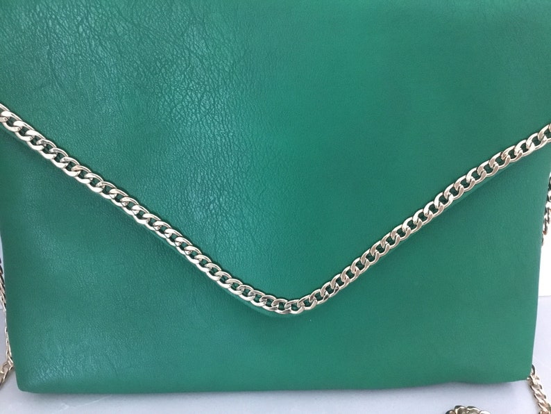 May include: A green leather clutch bag with a silver chain strap.
