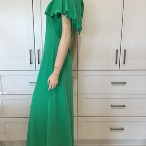 May include: A long, flowing green maxi dress with a ruffled neckline and short, ruffled sleeves. The dress is made of a soft, lightweight fabric and has a relaxed fit.