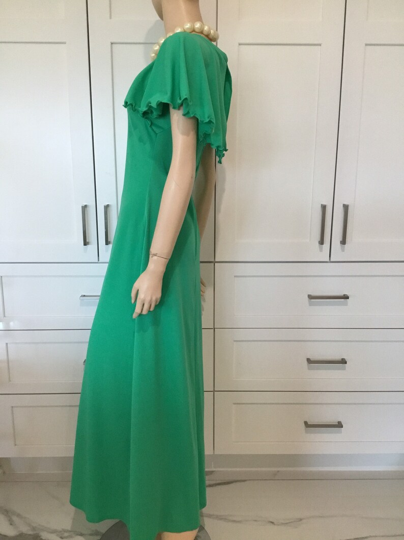 May include: A long, flowing green maxi dress with a ruffled neckline and short, ruffled sleeves. The dress is made of a soft, lightweight fabric and has a relaxed fit.
