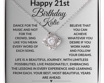 May include: A silver necklace with a knot pendant and clear crystals. The necklace comes in a box with a message that reads "Happy 21st Birthday Katie" and an inspirational quote about following your dreams.