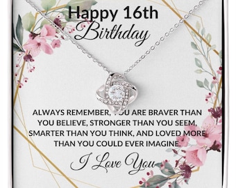 May include: A silver-toned necklace with a pendant featuring a central clear stone surrounded by smaller stones. The necklace is presented in a white box with floral and geometric designs. Text reads "Happy 16th Birthday" and "I Love You".