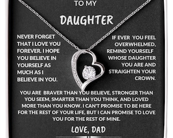 May include: A silver heart-shaped pendant necklace with a central clear gemstone, presented in a black box. The box contains a message to a daughter from her dad, with inspirational text.