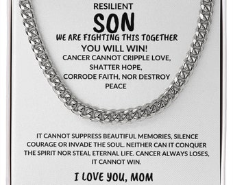 May include: A white box with a silver chain necklace inside. The box has a message printed on it that reads "To my amazingly resilient son, we are fighting this together, you will win! Cancer cannot cripple love, shatter hope, corrode faith, nor destroy peace. It cannot suppress beautiful memories, silence courage or invade the soul. Neither can it conquer the spirit nor steal eternal life. Cancer always loses, it cannot win. I love you, Mom."
