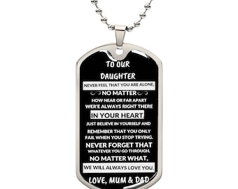 May include: A black dog tag necklace with a silver chain. The tag has a message for a daughter that reads "To our daughter, never feel that you are alone, no matter how near or far apart we're always right there in your heart. Just believe in yourself and remember that you only fail when you stop trying. Never forget that whatever you go through, no matter what, we will always love you. Love, Mum & Dad."
